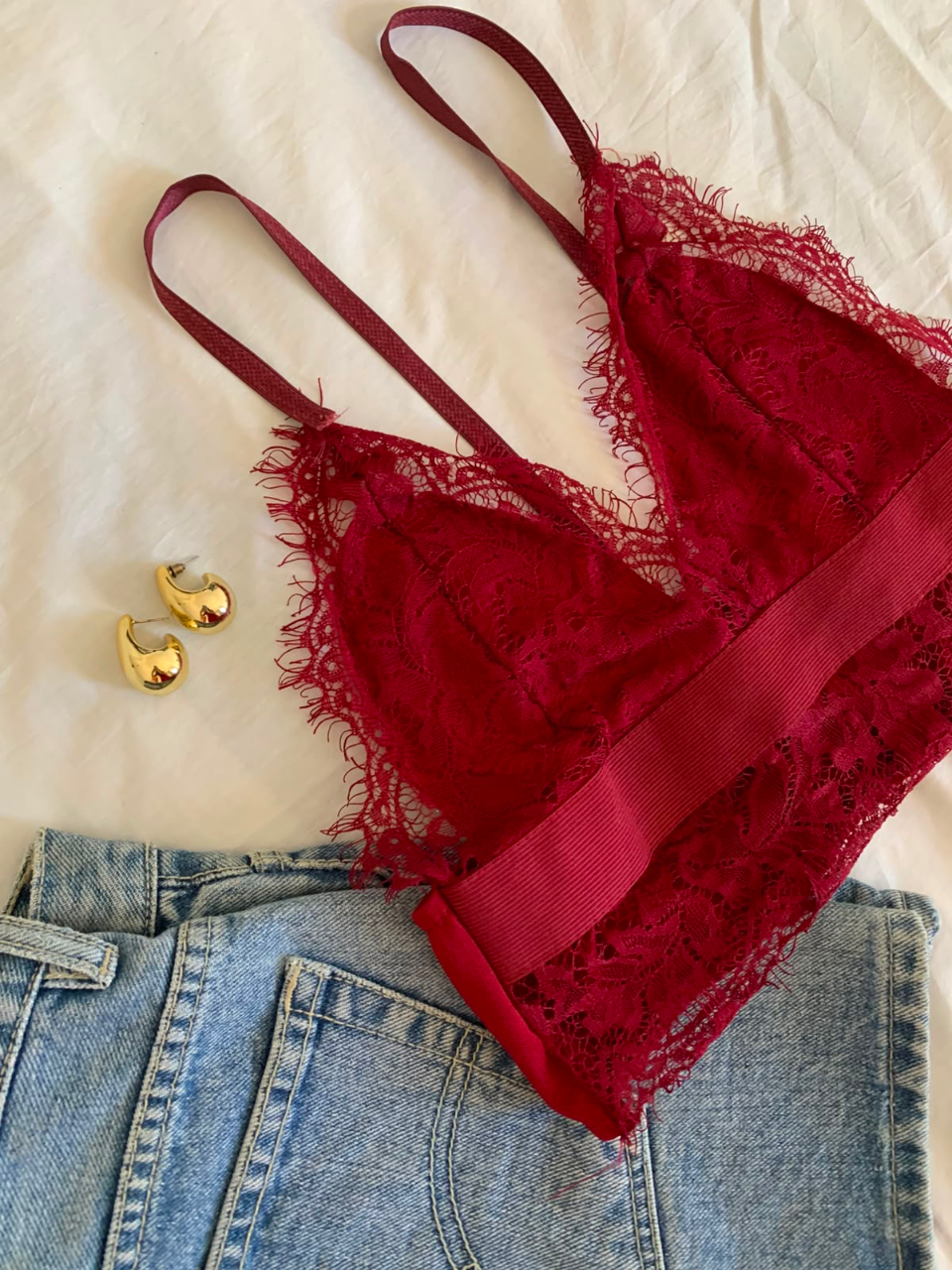 Top de renda vinho com brincos dourados e jeans